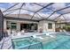 Screened-in pool and spa with built-in loungers, and a covered outdoor kitchen and dining area at 17604 Hickok Belt Loop, Bradenton, FL 34211