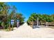 Sandy beach access with informational signs, native foliage, and a wooden walkway leading to the ocean at 2439 Sonoma W Dr, Nokomis, FL 34275