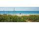 Picturesque Nokomis Beach scene with clear turquoise water, tall grass, and people enjoying a peaceful stroll at 2439 Sonoma W Dr, Nokomis, FL 34275
