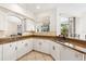 Clean kitchen with white cabinets and granite countertops, seamlessly flowing into the living area at 2439 Sonoma W Dr, Nokomis, FL 34275