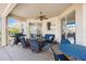 Covered patio has blue outdoor furniture, ceiling fan, and sliding glass doors to interior rooms at 2439 Sonoma W Dr, Nokomis, FL 34275