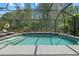 Screened-in pool area with a pool, lounge chairs, waterfall features, and trees in the background at 259 Golden Harbour Trl, Bradenton, FL 34212