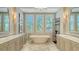 Elegant bathroom showcasing a standalone tub with windows, decorative shelving, and marble floors at 3153 Founders Club Dr, Sarasota, FL 34240