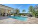 Beautiful backyard with a pool, waterfall feature, lush landscaping, and outdoor kitchen area at 3153 Founders Club Dr, Sarasota, FL 34240