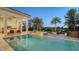 An in-ground pool and spa offer a relaxing view of lush landscaping, palm trees, and a serene lake at 3153 Founders Club Dr, Sarasota, FL 34240
