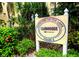 Sign indicating the direction to the clubhouse, surrounded by lush greenery and colorful flowers at 3719 Lake Bayshore Dr # H-204, Bradenton, FL 34205