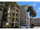 A condo building showcasing multiple balconies with beautiful palm trees and landscaped foliage around the property at 3719 Lake Bayshore Dr # H-204, Bradenton, FL 34205