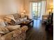 Comfortable living room with floral couches, dark floors, balcony access, and a modern television at 3719 Lake Bayshore Dr # H-204, Bradenton, FL 34205