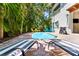 Relaxing backyard featuring a pool, lounge chairs, lush greenery, and palm trees, perfect for outdoor living at 4002 6Th Ave, Holmes Beach, FL 34217