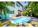 Inviting backyard with a private pool surrounded by lush greenery, sun loungers, and colorful chairs at 4002 6Th Ave, Holmes Beach, FL 34217