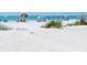 Beautiful sandy beach with grass, beachgoers, and colorful umbrellas on a sunny day at 4307 Gulf Dr # 202, Holmes Beach, FL 34217