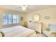 Light bedroom featuring a queen size bed, white dresser and plantation shutters at 4307 Gulf Dr # 202, Holmes Beach, FL 34217