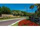 Community entrance with a stone sign, mature trees, and vibrant red flowers creating an inviting welcome at 4701 Chandlers Forde # 22, Sarasota, FL 34235