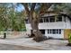Beautiful two-story home featuring mature tree, white picket fence, and a gravel patio with picnic table at 4705 Hollingsworth Ave, Sarasota, FL 34233