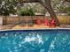 Backyard featuring a pool and wooden deck with seating surrounded by mature trees and a fence at 4705 Hollingsworth Ave, Sarasota, FL 34233