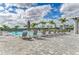 Relaxing pool area featuring lounge chairs, umbrellas, and lush palm trees against a bright blue sky with fluffy clouds at 5129 Marina Basin Ct, Bradenton, FL 34211