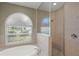 Well-lit bathroom featuring a soaking tub with a shower and a large window offering ample natural light at 5354 Nathaniel Pl, Sarasota, FL 34233