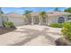 Charming home featuring a tiled roof, arched windows, columns, palm trees, and a paver driveway at 5354 Nathaniel Pl, Sarasota, FL 34233