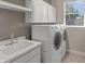 Laundry room with white washer and dryer beneath a window and cabinets at 5354 Nathaniel Pl, Sarasota, FL 34233