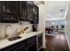 Home bar featuring custom cabinetry, beverage fridge, and view to the billiards room at 541 Fore Dr, Bradenton, FL 34208