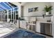 Outdoor kitchen area featuring a built-in grill, sink, counter space, and seating, perfect for al fresco dining and entertainment at 541 Fore Dr, Bradenton, FL 34208