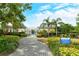 A paved walkway leads to the gated community entrance, framed by lush landscaping and manicured grounds under a blue sky at 7137 Orchid Island Pl, Bradenton, FL 34202