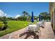 Outdoor patio with tables, chairs, and umbrellas overlooking a lake and well-manicured lawns at 7665 Bergamo Ave, Sarasota, FL 34238