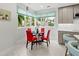Bright eat-in kitchen boasts breakfast nook with red chairs and views to lush tropical plants at 7782 Club Ln, Sarasota, FL 34238