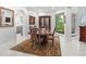 Formal dining room boasts elegant wood table with six chairs, antique cabinet, and large window with lush backyard view at 7782 Club Ln, Sarasota, FL 34238