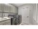 A laundry room is equipped with gray cabinets, washer, dryer and sink at 7782 Club Ln, Sarasota, FL 34238