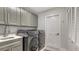 Laundry room with utility sink, grey cabinets, and front loading washer and dryer at 7782 Club Ln, Sarasota, FL 34238