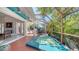Spa on a screened-in patio with views of the interior room, outdoor kitchen, and lush landscaping at 7782 Club Ln, Sarasota, FL 34238