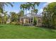 A lush green lawn and tropical landscaping surrounds the home's screened in pool area at 8024 Via Fiore, Sarasota, FL 34238