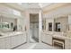 Bright bathroom with dual sinks, vanity area, and a glass-enclosed shower under a skylight at 8024 Via Fiore, Sarasota, FL 34238