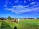 Golf driving range featuring players, lush green grass, and a beautiful cloudy sky at 8024 Via Fiore, Sarasota, FL 34238