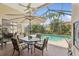 Screened-in patio with a dining table and umbrella overlooking the sparkling swimming pool and lush landscaping at 8024 Via Fiore, Sarasota, FL 34238
