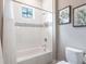 Bright bathroom featuring a white tub with shower, mosaic tile accent, and decorative wall art at 8265 Pavia Way, Bradenton, FL 34202