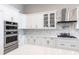 Close-up of the modern kitchen with stainless steel ovens, white cabinets, and decorative backsplash at 8265 Pavia Way, Bradenton, FL 34202