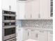 Modern kitchen details including stainless steel ovens, custom cabinetry, and mosaic backsplash at 8265 Pavia Way, Bradenton, FL 34202
