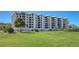 Sprawling condominium featuring a lush green lawn, tropical landscaping, and multi-level balconies at 8735 Midnight Pass Rd # 301B, Sarasota, FL 34242