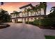 Elegant two-story home featuring stucco siding, a tile roof, arched entryways, and lush palm trees at 875 Siesta Key Cir, Sarasota, FL 34242