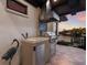Outdoor kitchen featuring stainless steel grill, stone backsplash, and sunset views over the water at 875 Siesta Key Cir, Sarasota, FL 34242