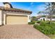 Spacious home garage with brick driveway and manicured landscaping, showcasing curb appeal under a sunny sky at 11200 Mcdermott Ct, Englewood, FL 34223