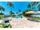 Captivating pool area with a brick patio, lounge chairs, sun umbrellas, and lush tropical landscaping at 12204 45Th Avenue W Dr, Cortez, FL 34215