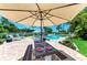 Charming poolside dining area with a picnic table set for a meal, shaded by a large umbrella at 12204 45Th Avenue W Dr, Cortez, FL 34215