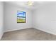 Bright bedroom featuring wood-look tile flooring, a ceiling fan, and a window with natural light and views at 12396 Bacchus Rd, Port Charlotte, FL 33981