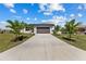 Charming one-story home featuring a well-manicured lawn, palm trees, and a brown two-car garage at 12396 Bacchus Rd, Port Charlotte, FL 33981