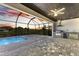A screened-in lanai features an outdoor kitchen and a stunning pool with a tranquil view of the sunset over the water at 12396 Bacchus Rd, Port Charlotte, FL 33981