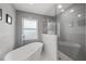 Modern bathroom featuring gray tile walls, a glass-enclosed shower, and a freestanding soaking tub at 1647 Siesta Dr, Sarasota, FL 34239