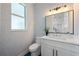 Modern bathroom with gray wallpaper, and white vanity with a mirror and an accent light at 1647 Siesta Dr, Sarasota, FL 34239